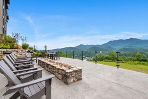 Une terrasse extérieure avec des fauteuils Adirondack, un foyer en pierre et une vue sur les montagnes.