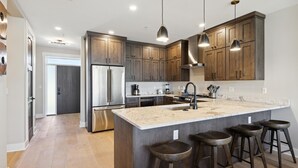 Una cocina moderna con armarios de madera, electrodomésticos de acero inoxidable y una isla grande con taburetes de bar.