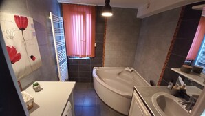 A bathroom with a bathtub, a toilet, and a sink. There is a window with curtains, a towel rack, and a small plant. - Appartement T3, Jardin, Parking (Chaponost)