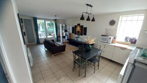 A modern kitchen with a dining area, a sofa, and a large window. - Appartement T3, Jardin, Parking (Chaponost)