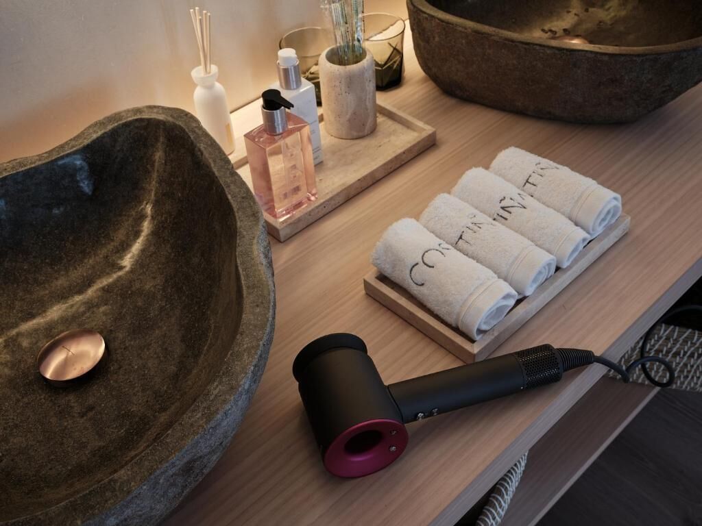 Un baño con lavabo de piedra, secador de pelo, toallas y artículos de aseo.