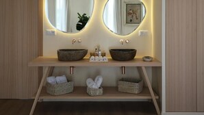 A bathroom with two round mirrors, a wooden vanity, and three wicker baskets under the counter. - Retiro Costiña Wellness&Villas (Santa Comba)