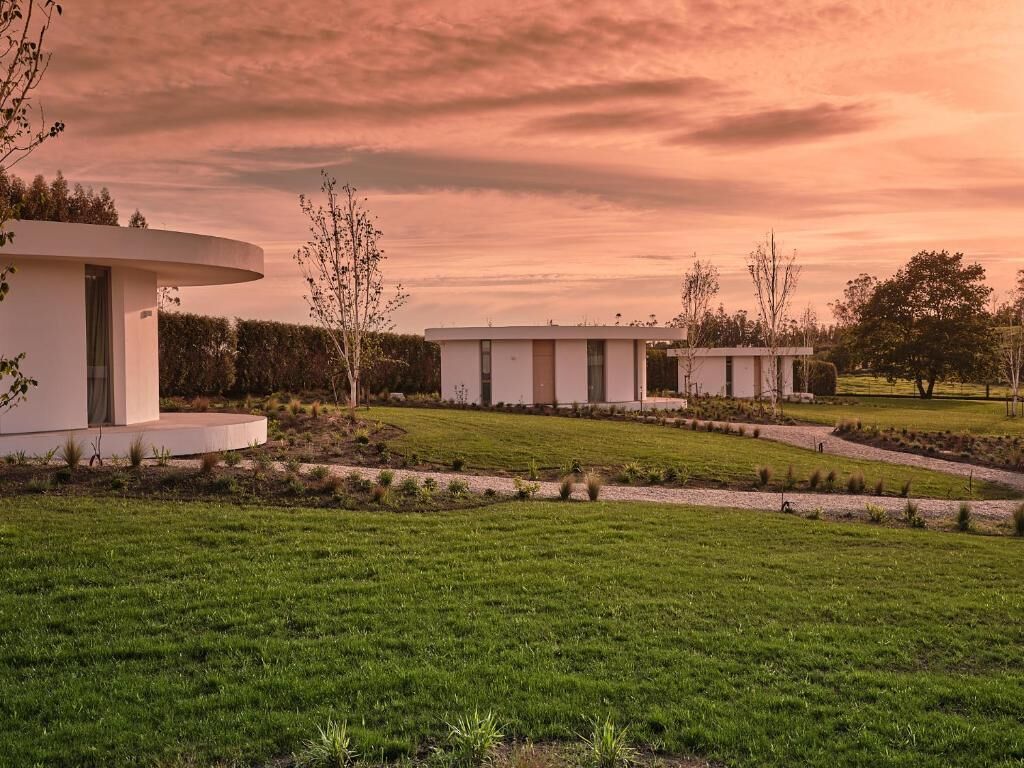 A modern building with a circular structure and a rectangular building, surrounded by well-maintained lawns and pathways.