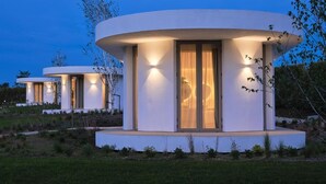 A modern, circular building with a flat roof, large windows, and a well-lit exterior. - Retiro Costiña Wellness&Villas (Santa Comba)
