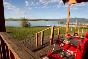 Une terrasse en bois offrant une vue sur un lac et des bateaux.
