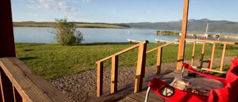 Una terraza de madera con vista a un lago y barcos.