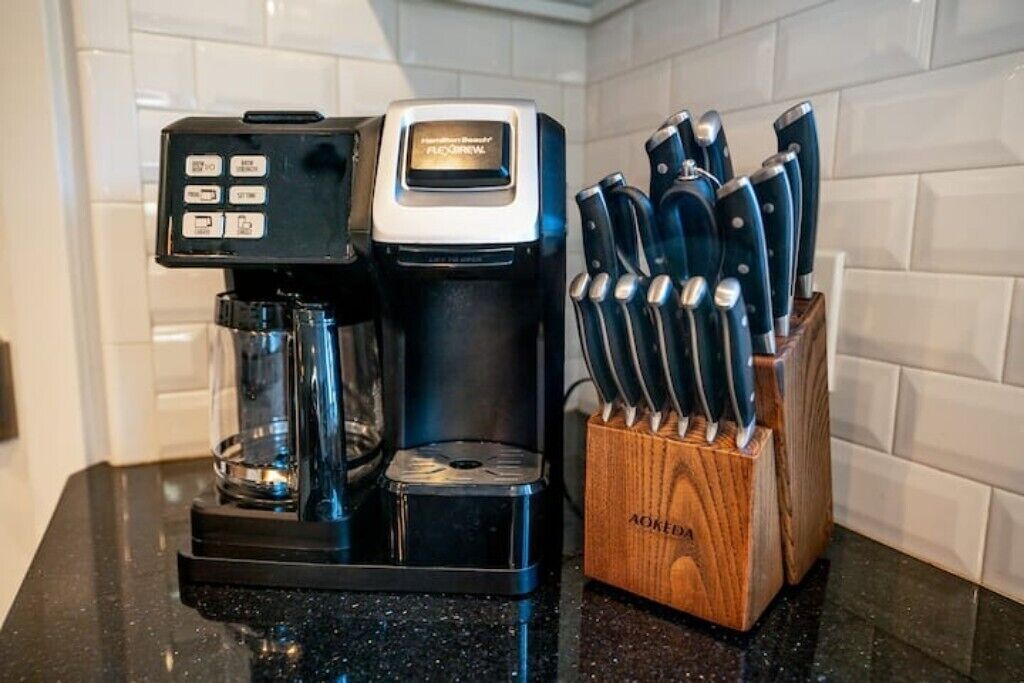 A coffee maker with a control panel and a knife block with several knives.