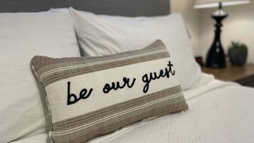 A bed with a pillow that reads "be our guest."