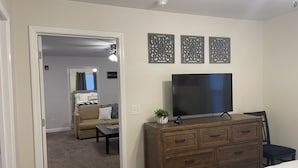 Habitación de hotel con una cama grande, un aparador de madera, un televisor de pantalla plana y un espejo.