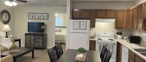 Una cocina moderna con armarios de madera, refrigerador, estufa, microondas y un comedor con mesa y sillas.
