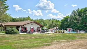Un bâtiment de style rustique, avec un toit rouge et des murs blancs, doté d’une terrasse et d’un espace piscine extérieur.