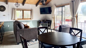 Un salon confortable avec une cheminée, un téléviseur et un coin repas comprenant une table et des chaises.
