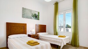 Hotelkamer met twee bedden, een nachtkastje, een lamp, een schilderij en een raam met gordijnen.