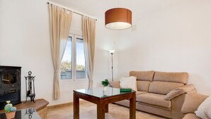 Een woonkamer met een bank, een salontafel met glazen blad, een vloerlamp en een open haard.