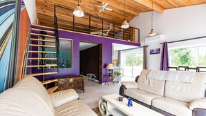 Ein modernes Wohnzimmer mit einer Couch, einem Couchtisch, einer Treppe und Blick ins Freie.