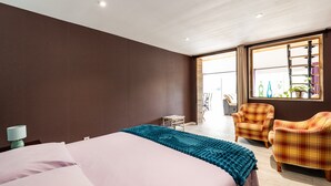 Ein Schlafzimmer mit einem Bett, zwei Stühlen, einem kleinen Tisch und einem Fenster mit Ausblick.