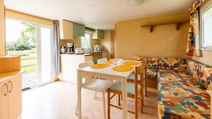 Un espacio habitable pequeño con una mesa de comedor, sillas, un sofá y una kitchenette.