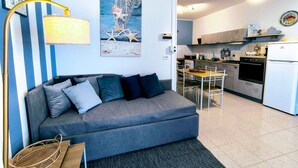 Una sala de estar moderna con un sofá, una lámpara y un cuadro de una playa.