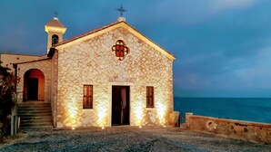 Un edificio de piedra con una torre de campanas, una cruz y un letrero que indica que es una iglesia.