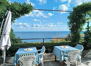 An outdoor seating area with tables and chairs, overlooking a body of water.