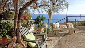 Eine Terrasse mit einer Bank, einem Tisch und Blumentöpfen.