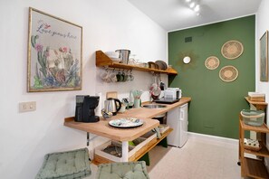 A compact kitchen with a wooden countertop, hanging utensils, and a green accent wall.