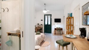 Ein Zimmer mit einem Bett, einem Schreibtisch, einem Stuhl, einer Kaffeemaschine und einem Fernseher.
