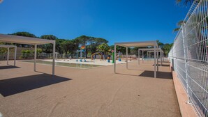 An outdoor playground with play structures, a fenced area, and trees in the background. - Mobile Home 'Mobilhome Oasis Village Puget Argen' with Shared Pool and Private Terrace (Puget-sur-Argens)