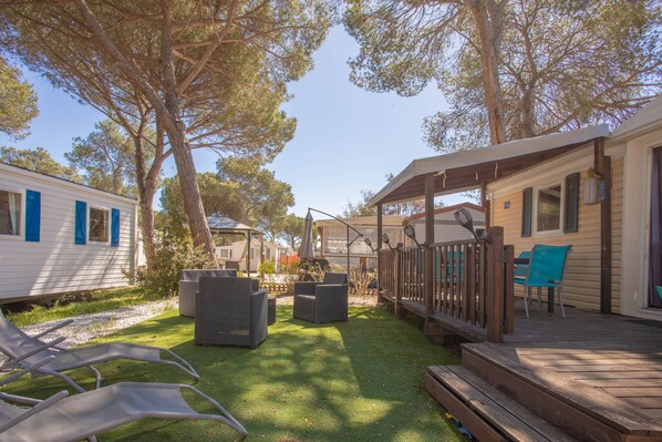 A deck with outdoor furniture, a covered area, and a grassy yard.
