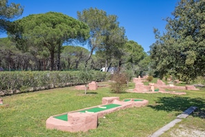 A park with green pathways, trees, and stone structures.