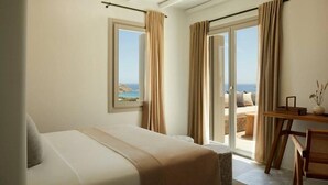 Une chambre avec un lit, un bureau et une vue sur la mer.
