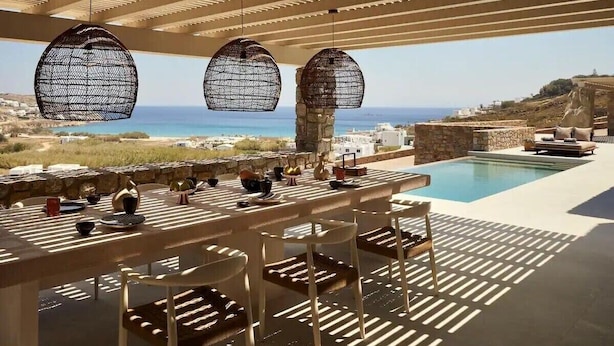 Un espace extérieur aménagé pour les repas, avec une piscine, offrant une vue sur le paysage côtier.