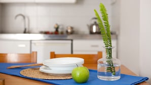 Una cocina con armarios blancos, un fregadero y una mesa de comedor con un mantel individual azul.