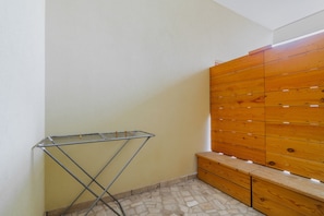 Une pièce comprenant un étendoir métallique, un banc en bois et un mur recouvert de lattes de bois disposées horizontalement.