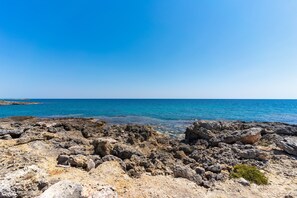 Eine felsige Küstenlandschaft mit klarem, blauem Meer und Himmel.