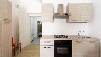 Een koelkast, een kookplaat, een waterkoker, kookgerei, borden en bestek