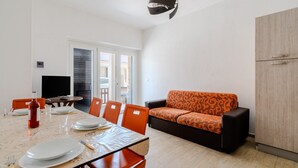 Un coin repas avec une table dressée pour quatre personnes, un canapé et un meuble.