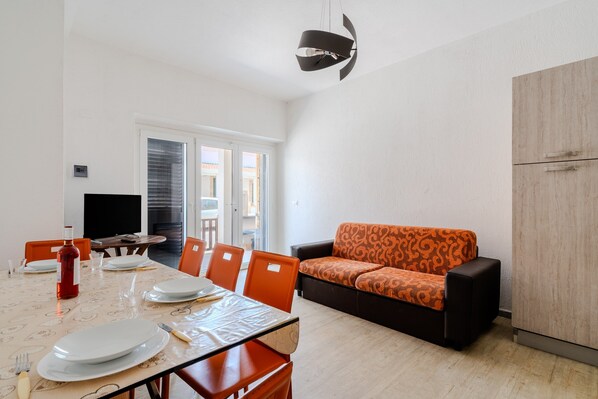 A dining area with a table set for four, a sofa, and a cabinet.