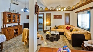 A traditional living room with a sofa set, a wooden cabinet, and a dining table.