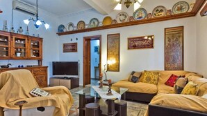 A living room with a sofa, armchair, TV, and decorative items.