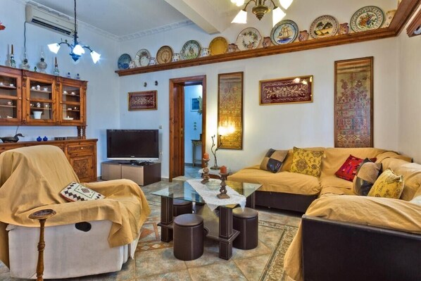 A living room with a sofa, armchair, TV, and decorative items. - Holiday Home 'Villa Ntora' with Mountain View, Wi-Fi and Air Conditioning (Afiartis)