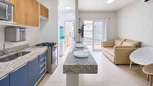 A modern kitchen with a granite countertop, built-in microwave, and stainless steel appliances. - Beach Praia Grande Ubatuba (Ubatuba)