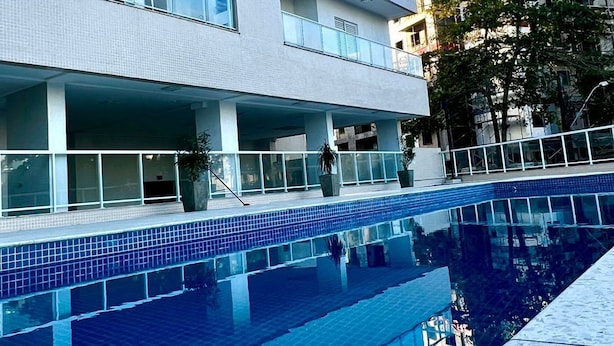 A modern building with a pool, featuring multiple balconies and a clear blue sky. - Beach Praia Grande Ubatuba (Ubatuba)