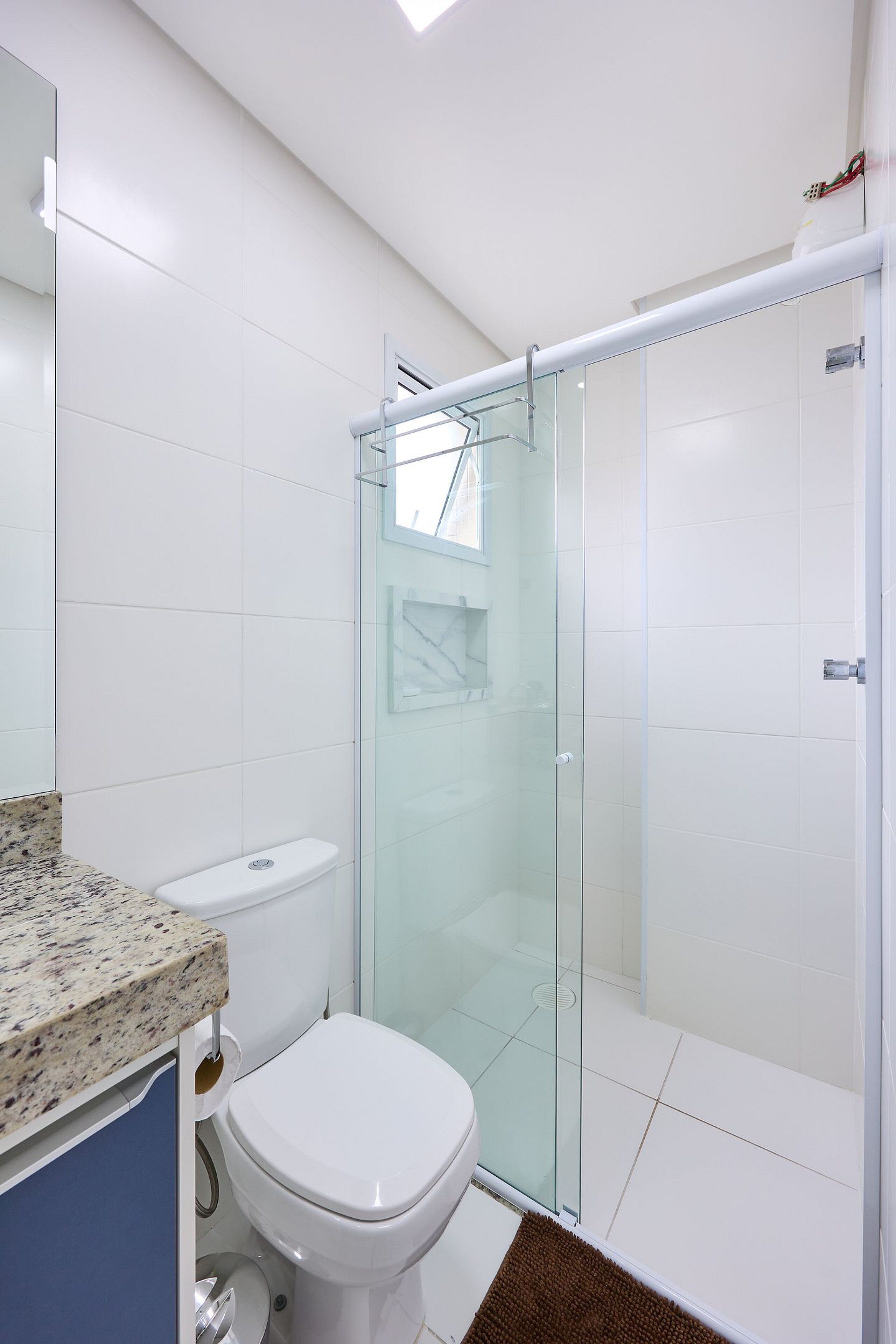 A bathroom with a glass-enclosed shower, a white toilet, and a marble countertop.
