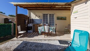 Un patio con mesa y sillas, una parrilla y un área cubierta con vistas al cielo.