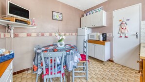 Cuina petita amb taula de menjador, cadires, nevera i microones.