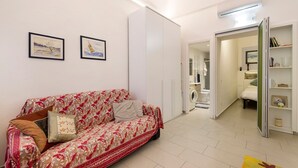 A room with a sofa, a wardrobe, a bed, a shelf with books, and framed pictures on the wall. - Apartment 'Smart Home Loano' with Wi-Fi and Air Conditioning (Loano)