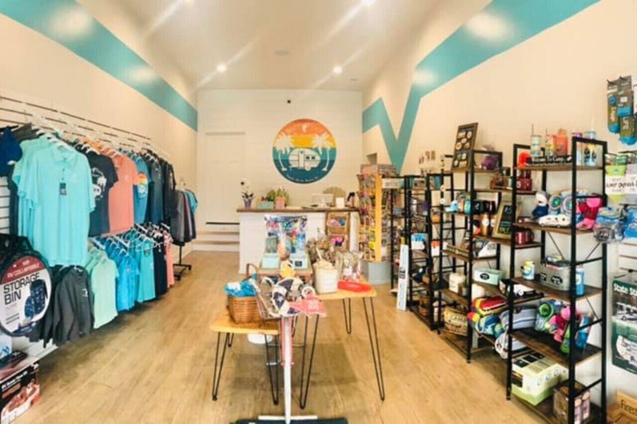 A clothing store with racks of clothes, a central table with items, and shelves on the right.