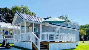 A two-story house with a covered porch, a small deck, and a golf cart parked in front. - Vacation Cottage North Myrtle Beach #68 (North Myrtle Beach)