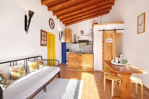 Una stanza con un letto, un tavolo da pranzo in legno, un angolo cottura e un bagno.